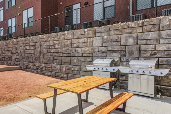 A picturesque picnic and grill area nestled within the Views of Music City in Nashville, TN, complete with a sturdy table perfect for outdoor dining amidst the lush surroundings.